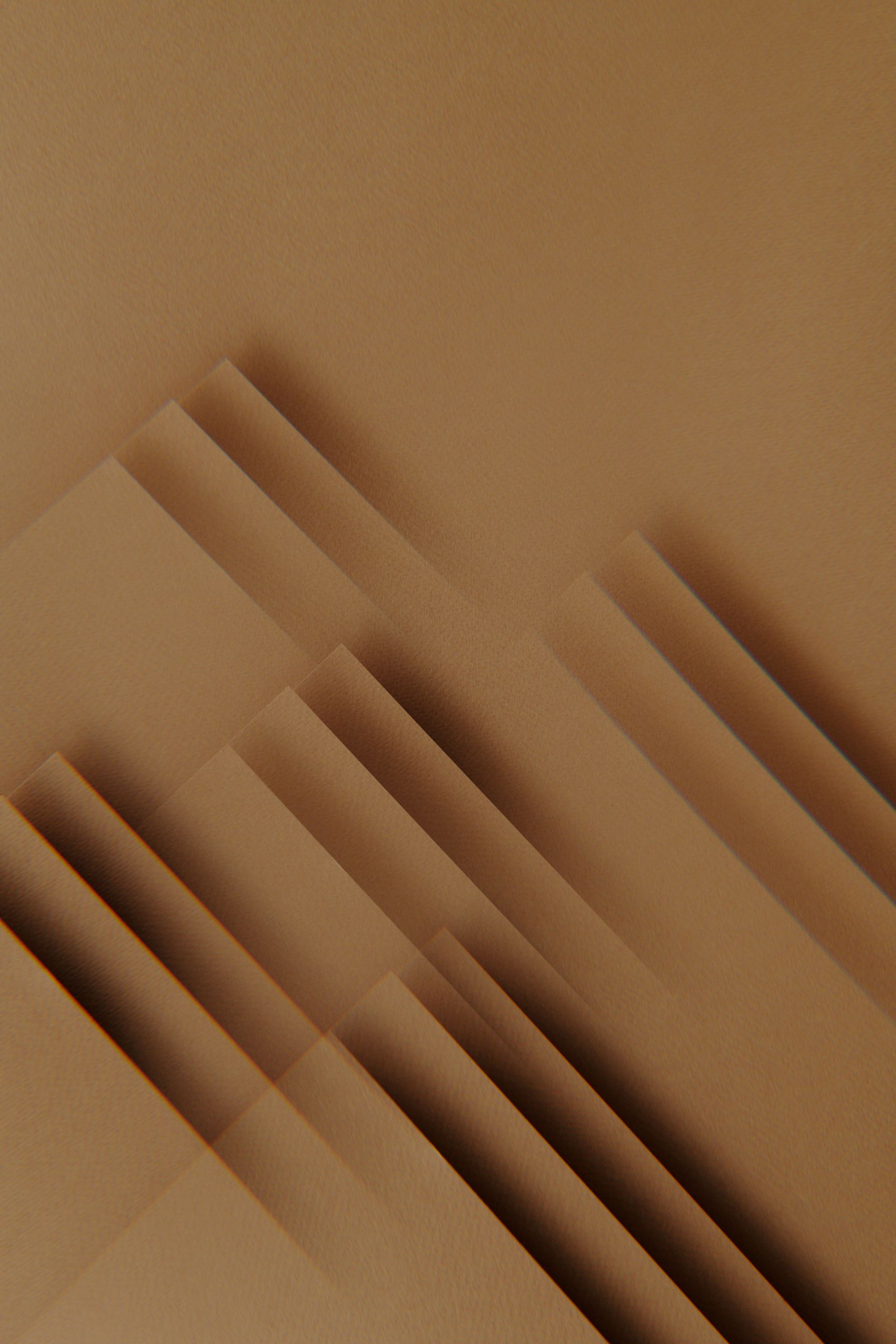 Sich überlappende Blätter aus hellbraunem Papier, die geometrische Schatten erzeugen.